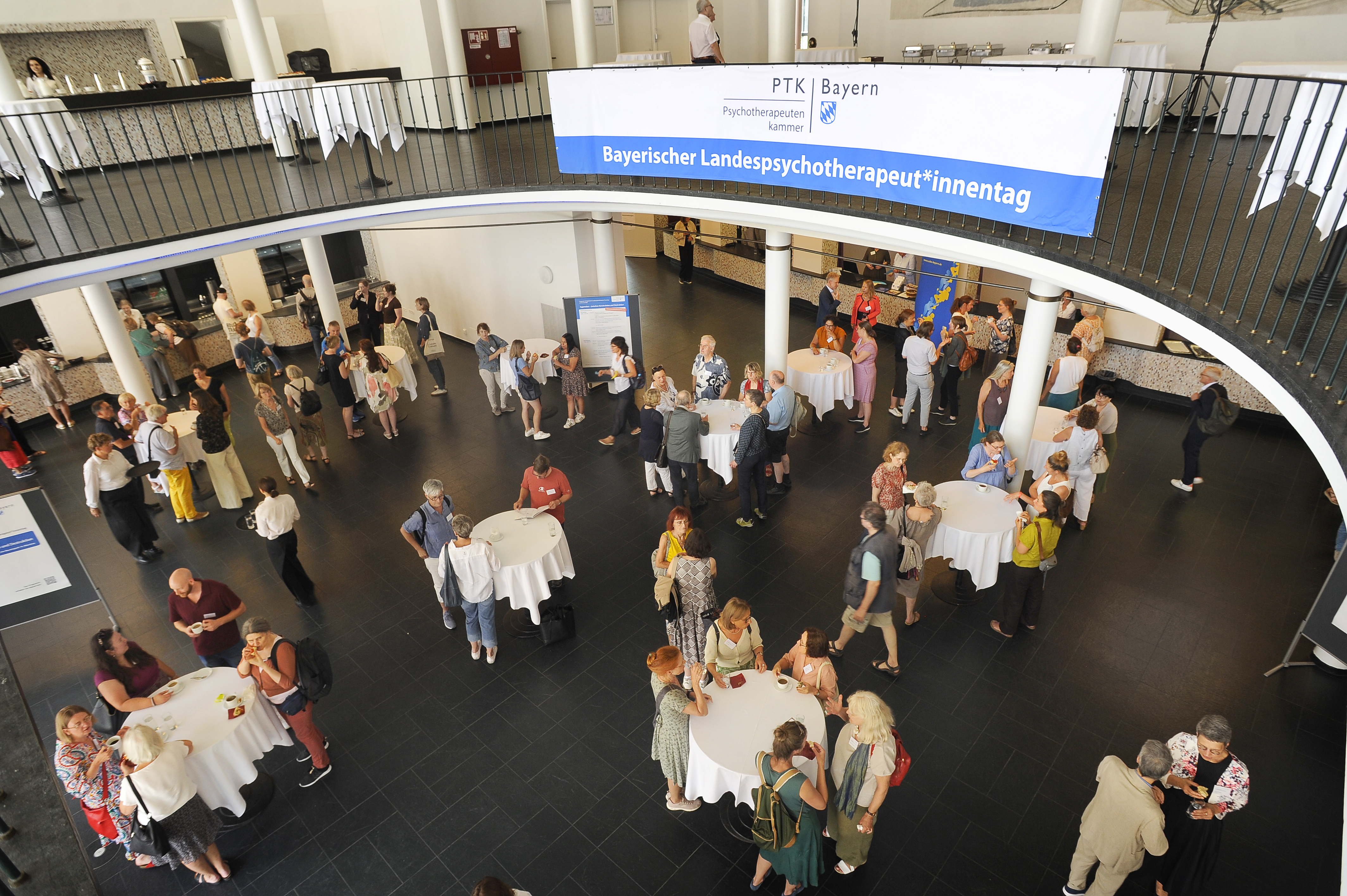 Ein Veranstaltungsfoyer mit in Grüppchen stehenden und sich unterhaltenden Menschen.